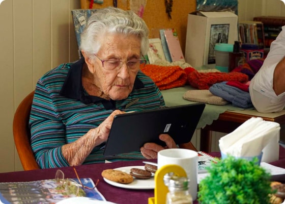 conpago client older woman sitting at a table using the app on her tablet