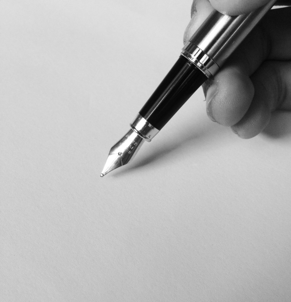 Main tenant un stylo plume et écrivant sur une page blanche.