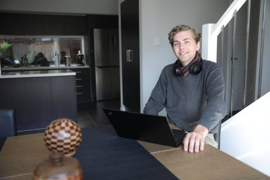 Young man sitting in kitchen with laptop