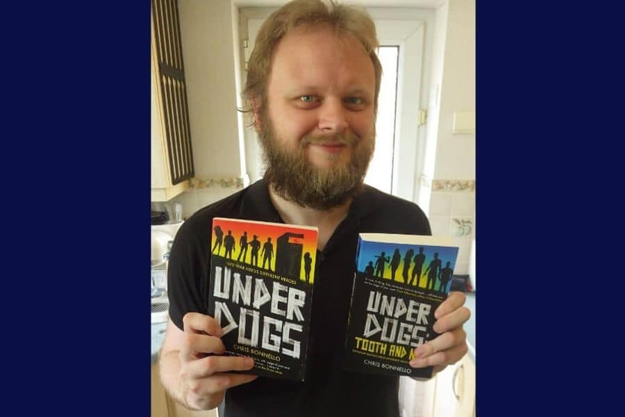 Chris Bonnello holding his two books and smiling