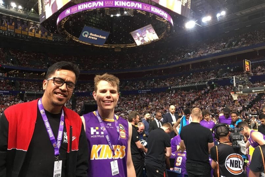Young man with friend at indoor basketball stadium full of people
