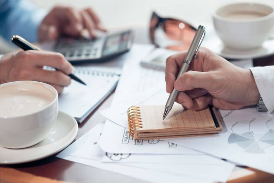 Two people with pens in hand and calculators