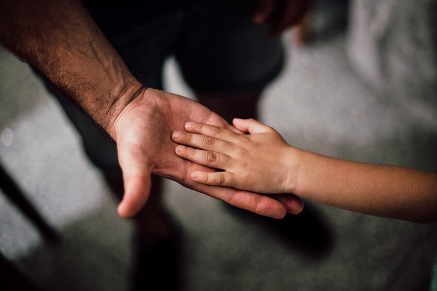 Childs hand in the palm of adult mans hand