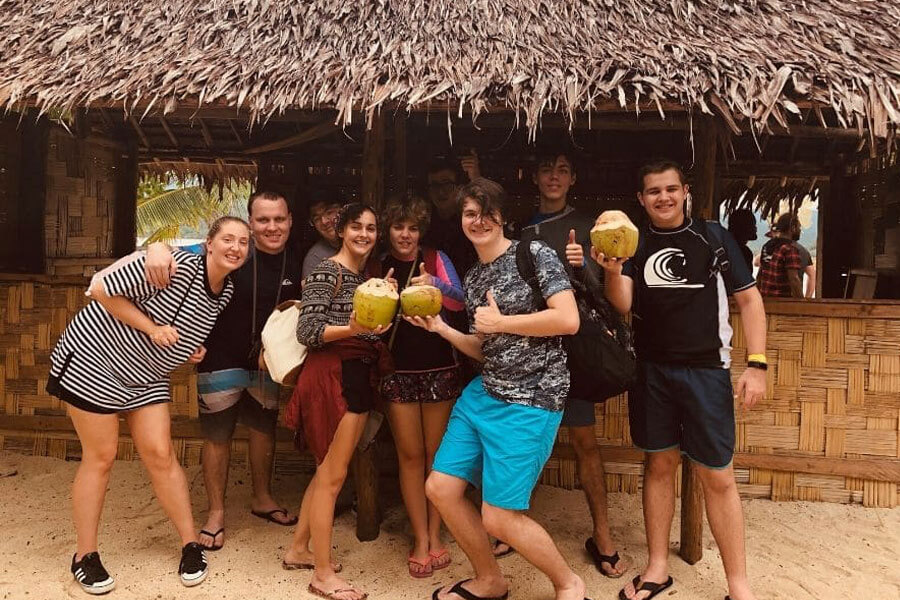Group of people drinking coconuts under a bungalow