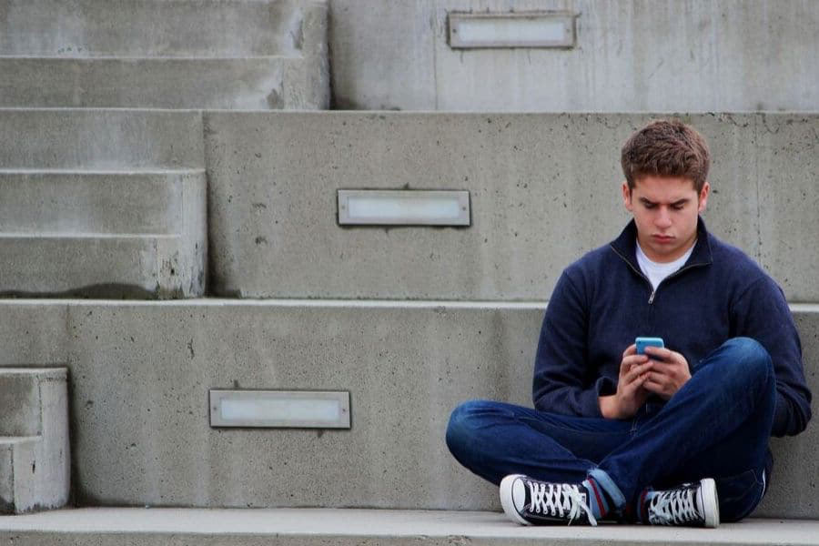Teenager sitting on steps with phone in hand