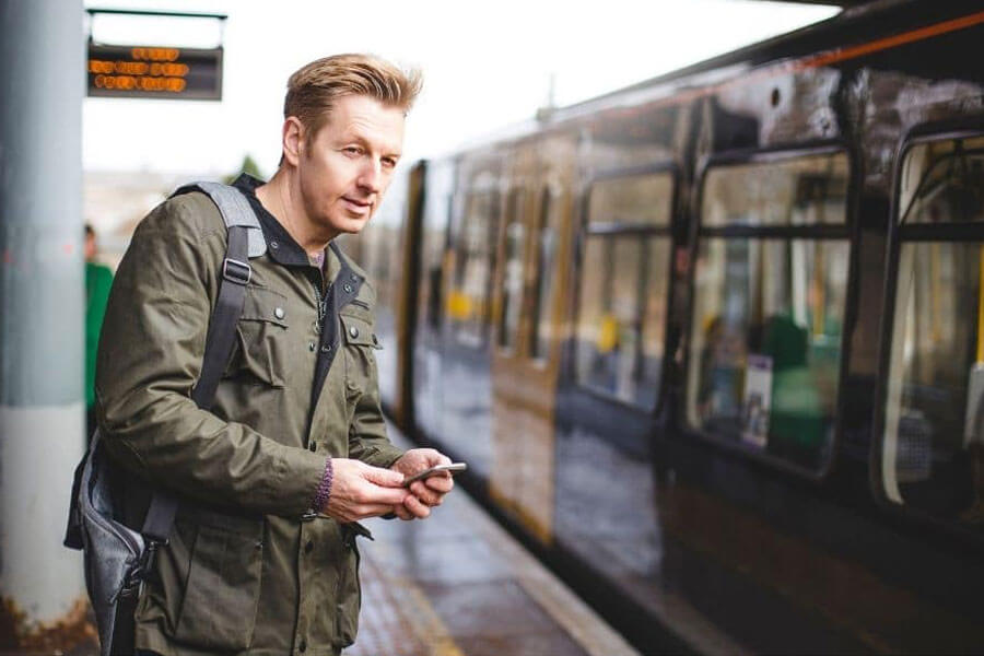 Young man on train station with phone in hand