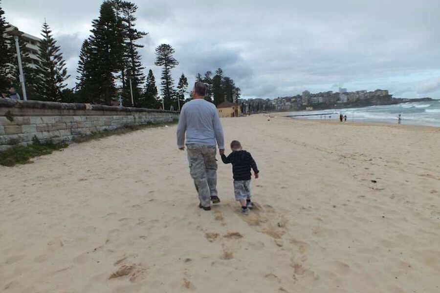 Boy walking on beach with his dad