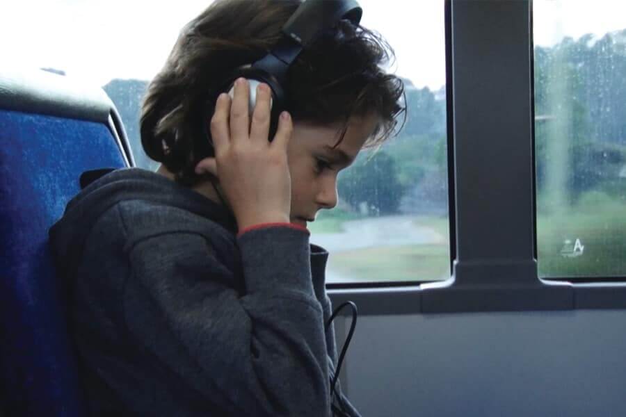 Boy with headphones on and hands up holding the headphones