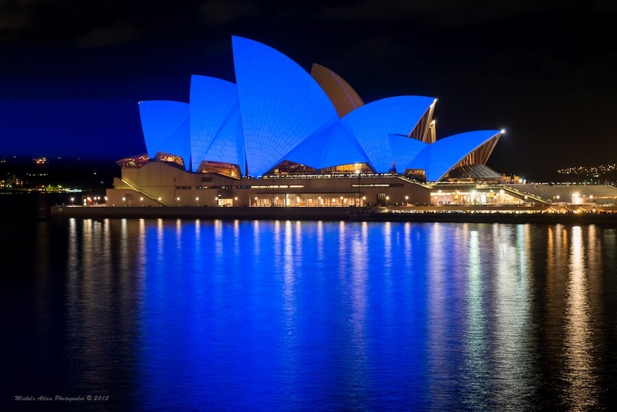 Sydney opera house lit up in blue lights at night