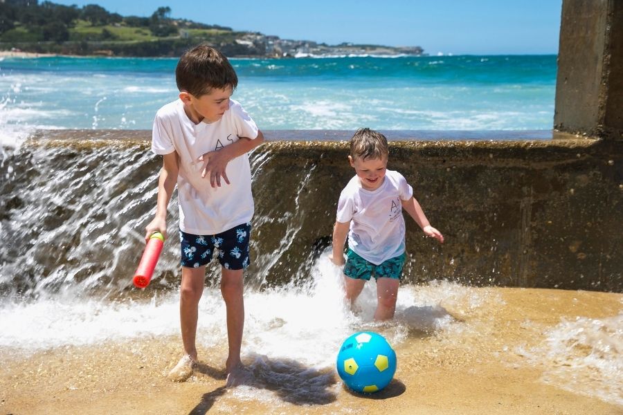kids splashing in water at beach on a sunny day