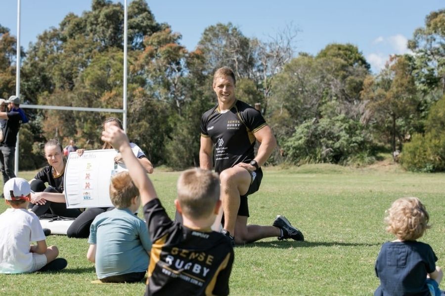 autistic children on a rugby field looking at visual chart and rugby occupational therapist