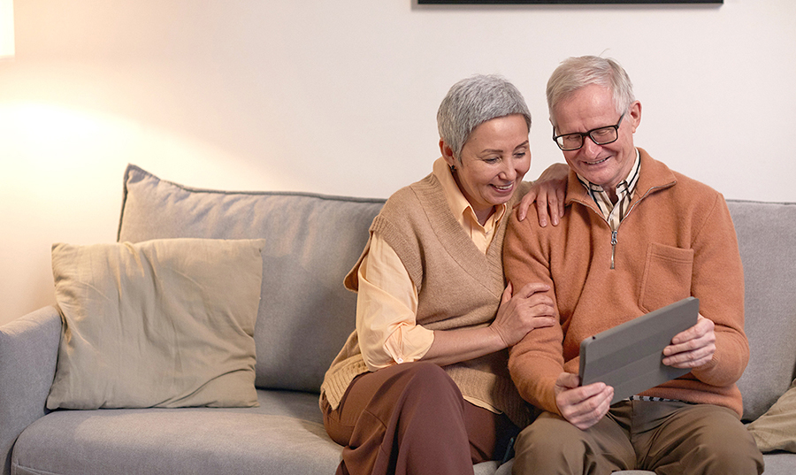 Happy couple uses ipad while sitting on couch