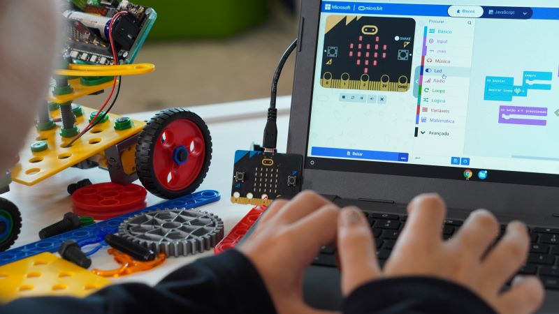 Conheça 7 recursos educacionais digitais para usar na sua escola 2 menino estudante programando placa da micro:bit e construindo um robô