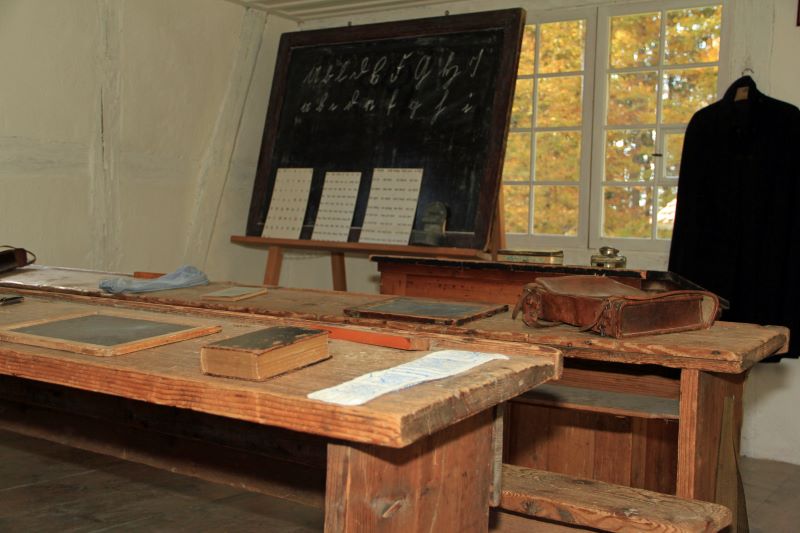 Edtech: o que é e quais os principais tipos 1 Foto de escola do século XIX, com bancos-carteiras, livros e lousas negras.