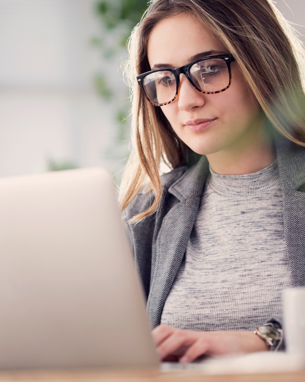 Woman with glasses working on laptop.