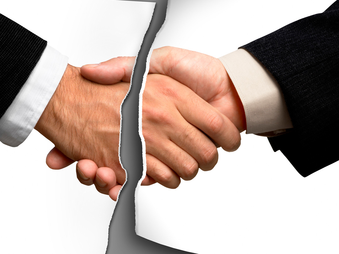 Two extended arms in suits with white skin shaking hands with a paper tear in the centre.