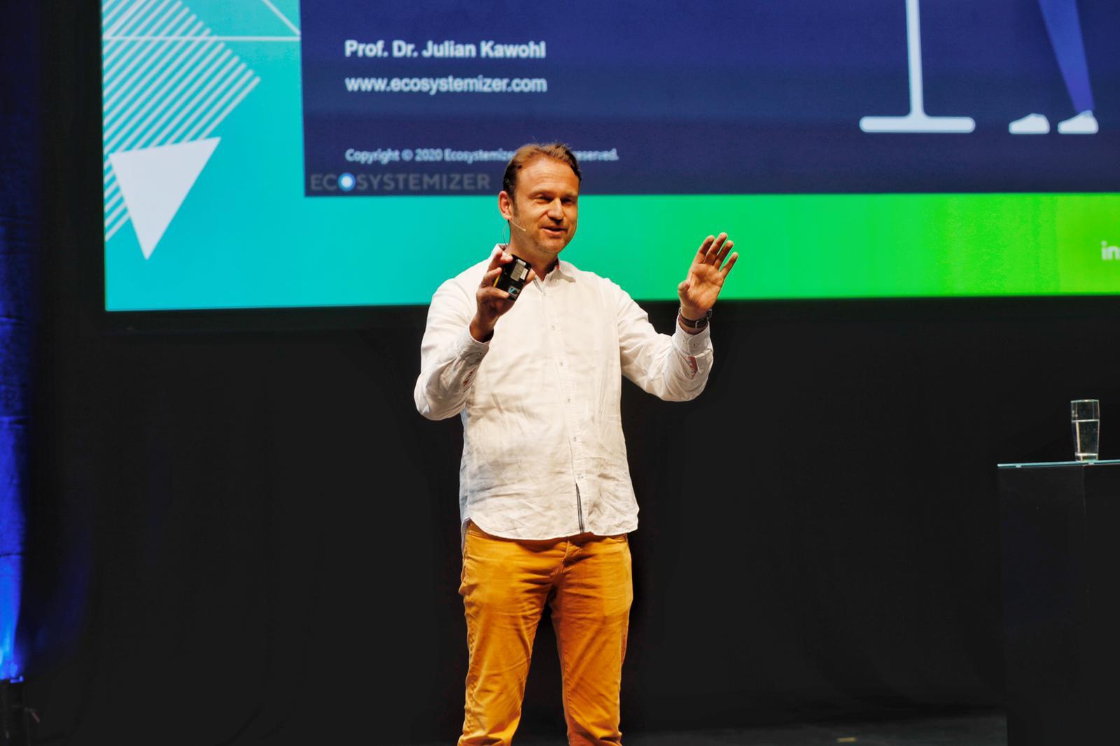 Julian Kawohl talks about ecosystems on a stage of audience.