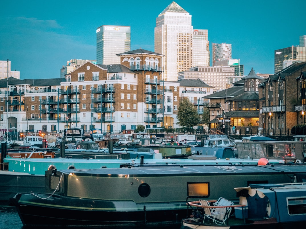 a scene of narrow boats, with residential and high rise banking buildings in the background.