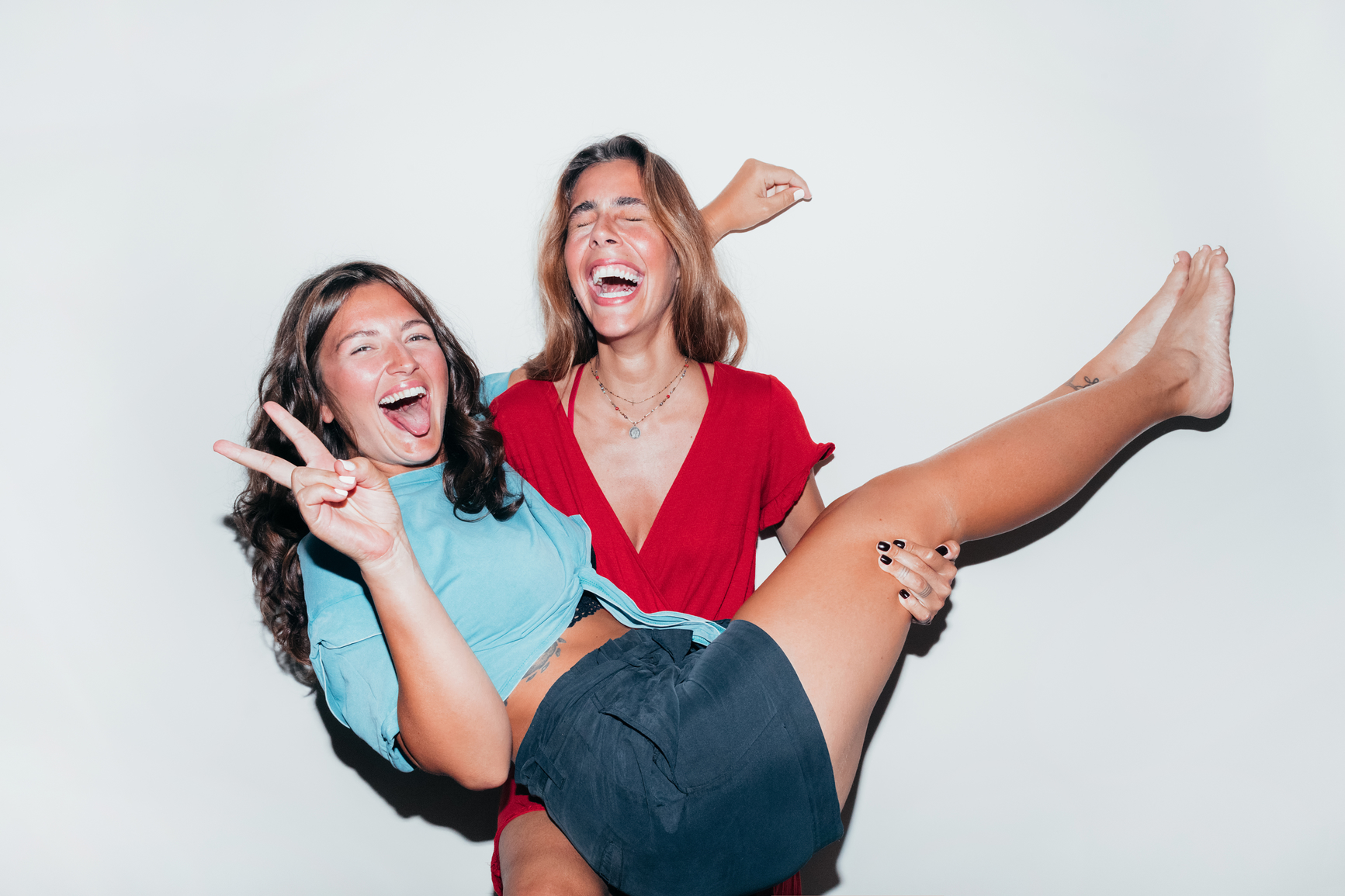 One friend holding another in her arms as they both laugh