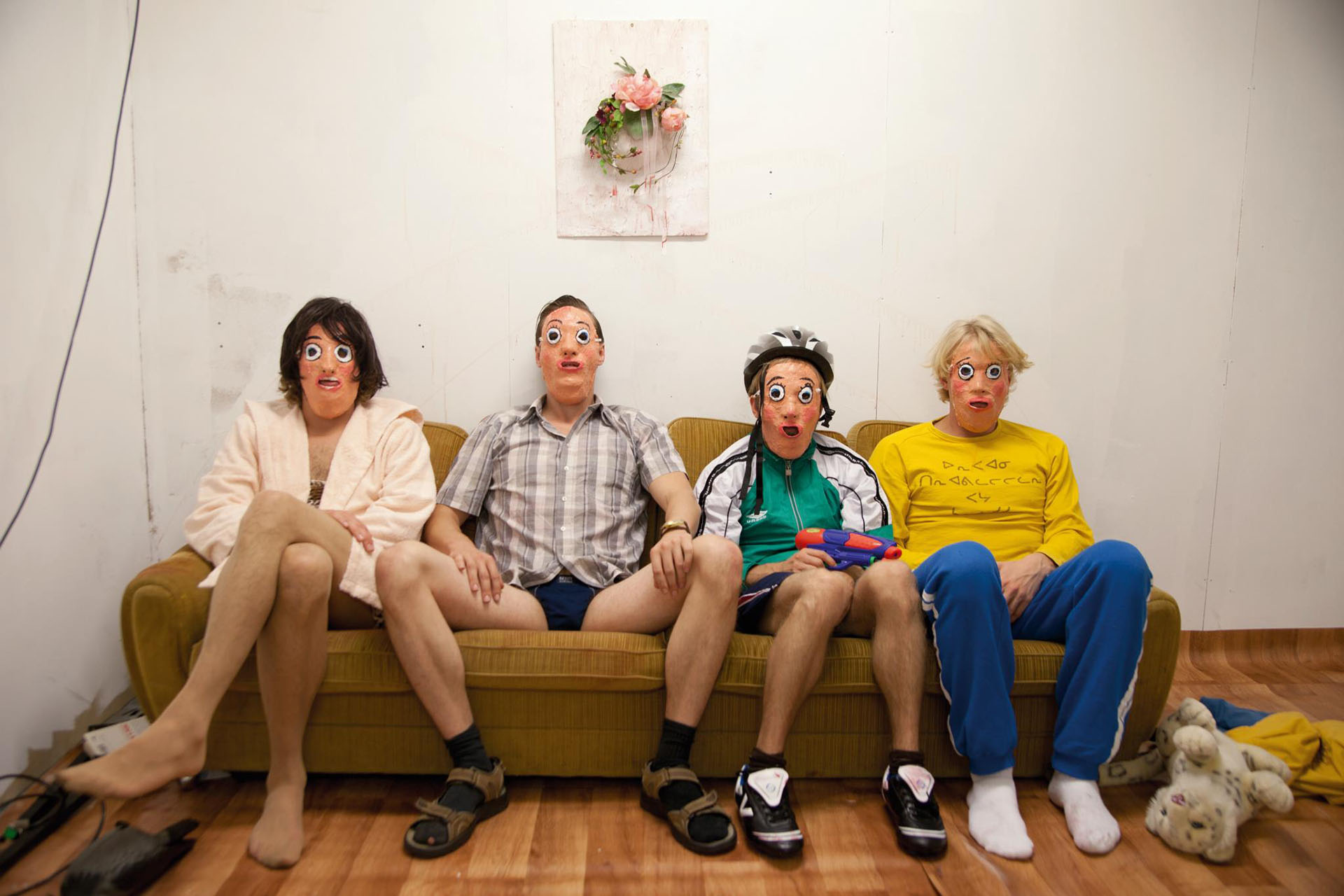 Four people in a sofa with strange face masks