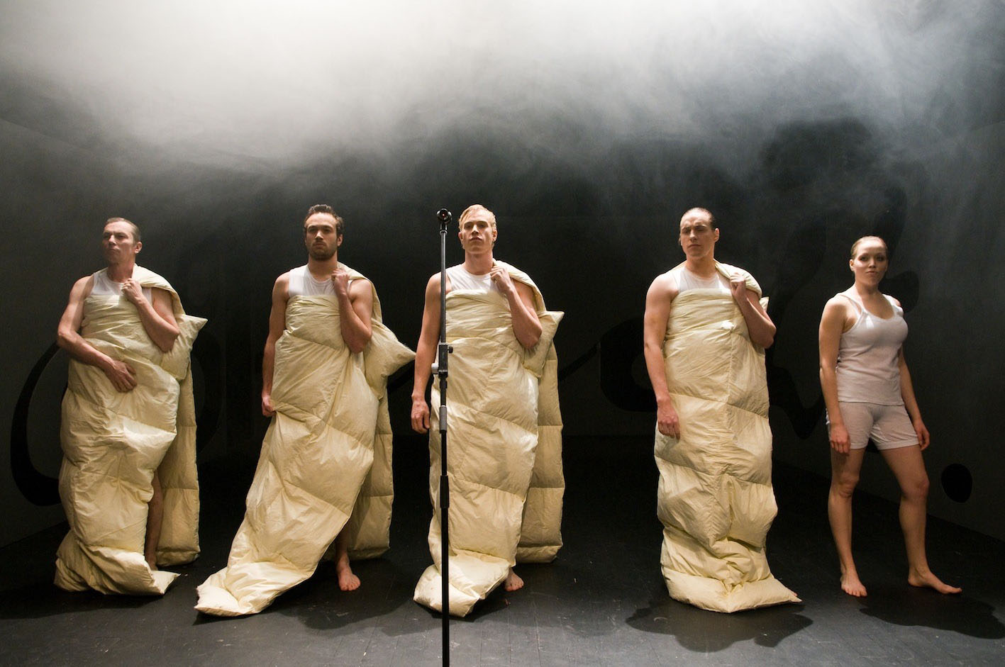 Five people standing n a stage with white fabric around them