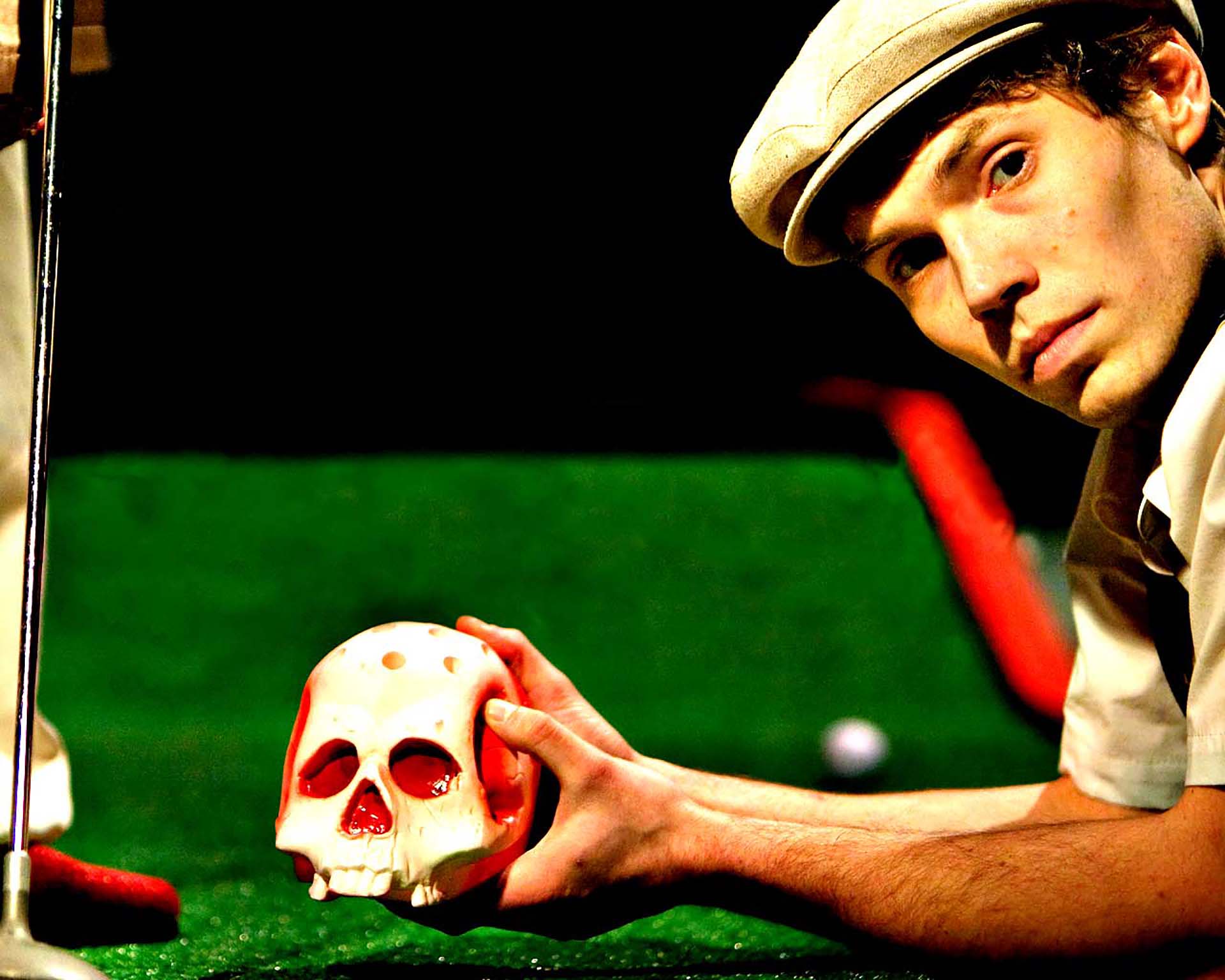 A man with a hat playing golf with a skeleton head