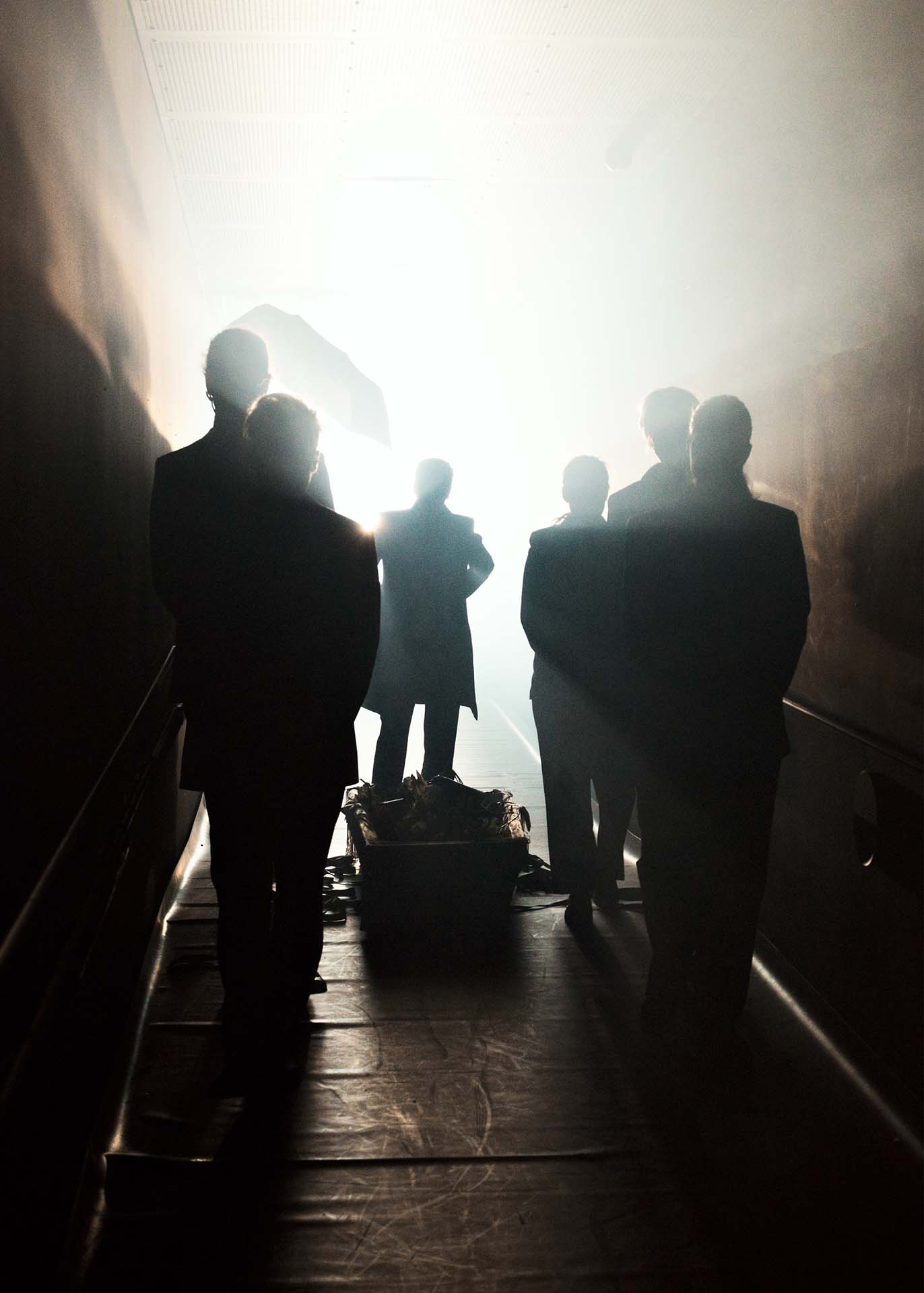 A group of people standing in a small passage with light from the front