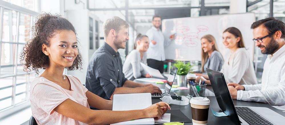 Young professional woman sitting in meeting with coworkers.