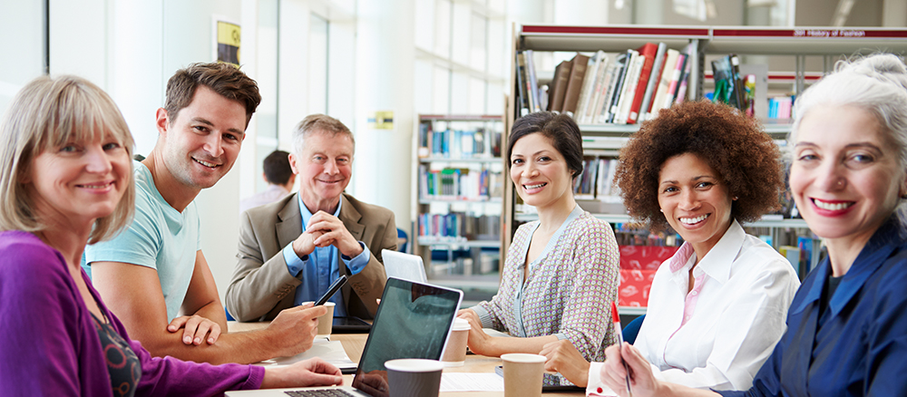 Young professional woman sitting in meeting with coworkers.