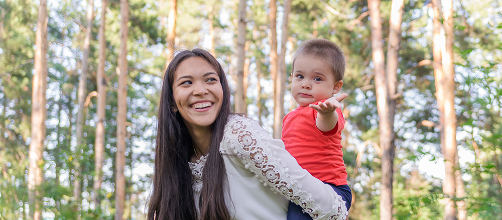 A happy young mother plays and has fun with her little son in the sun on a warm spring day.