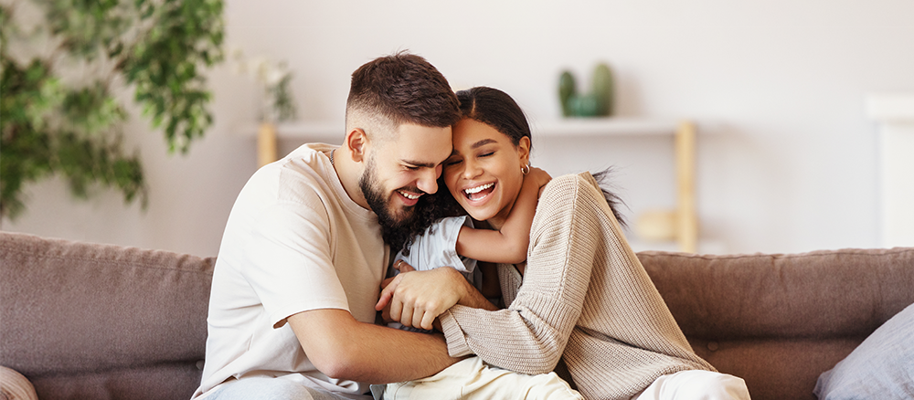 Happy mother, father and son hugging on a couch at home.
