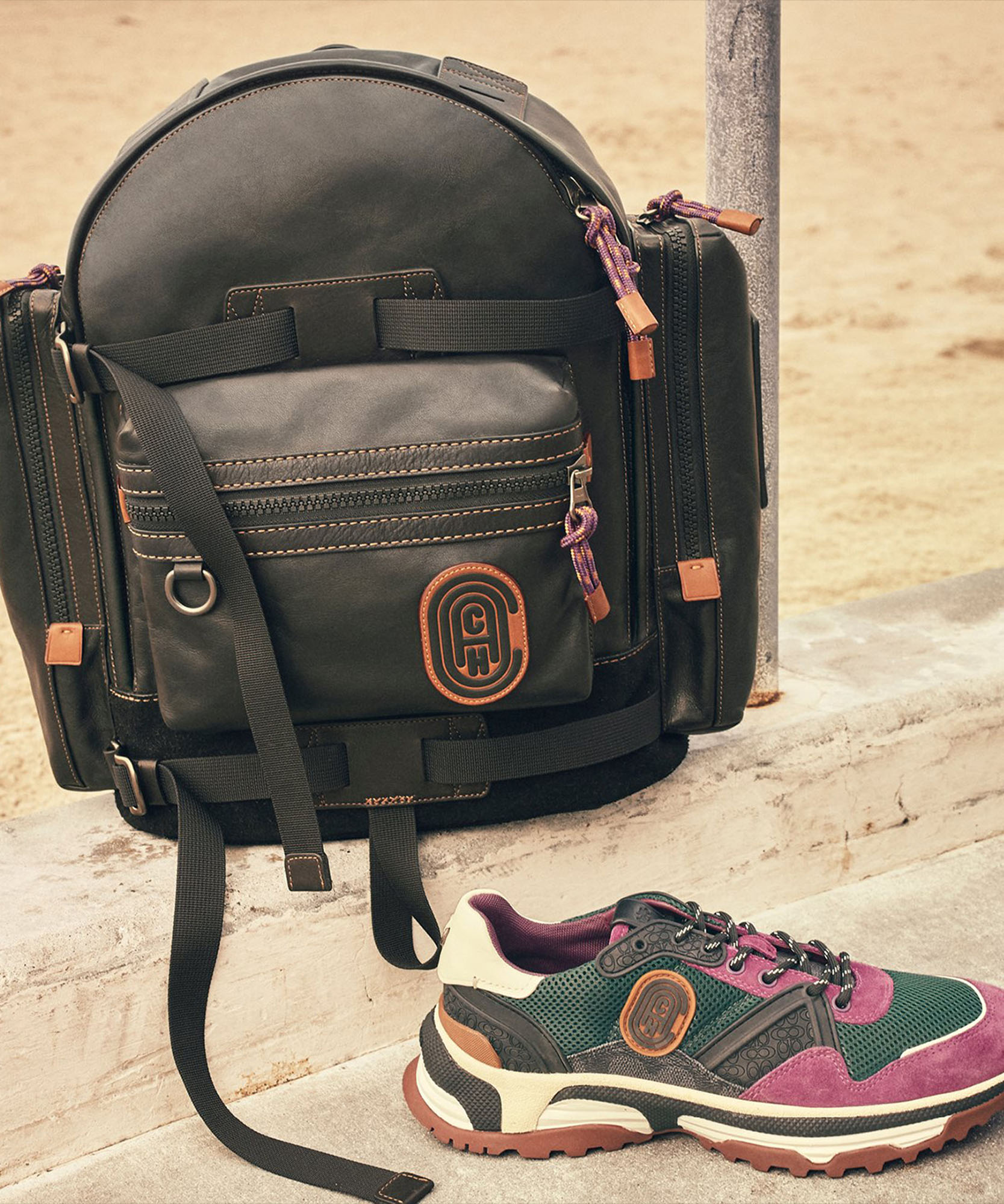 photo of black backpack and purple shoe both with coach logo imprinted on them