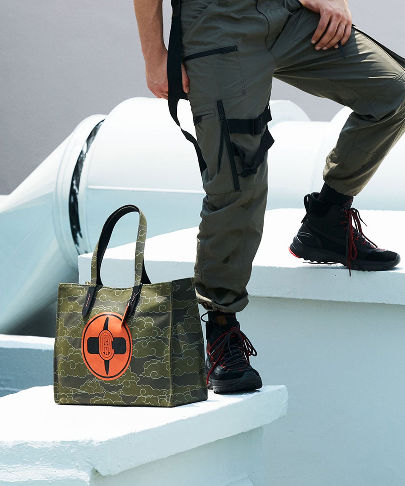 photo of green bag with a orange coach logo beside a models legs