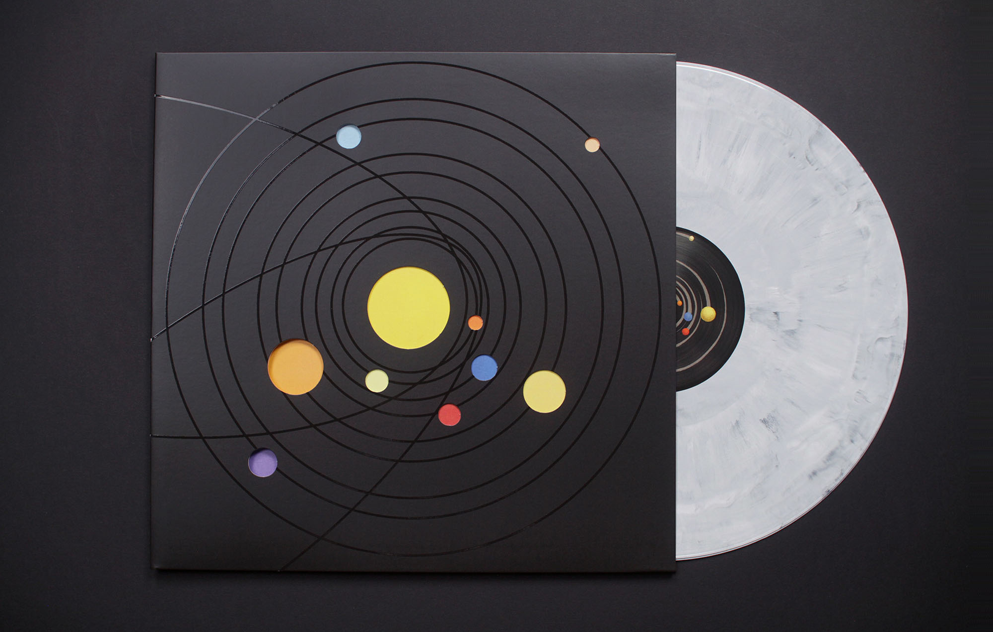 a photo of a grey vinyl half way outside of a black vinyl cover with colored circles