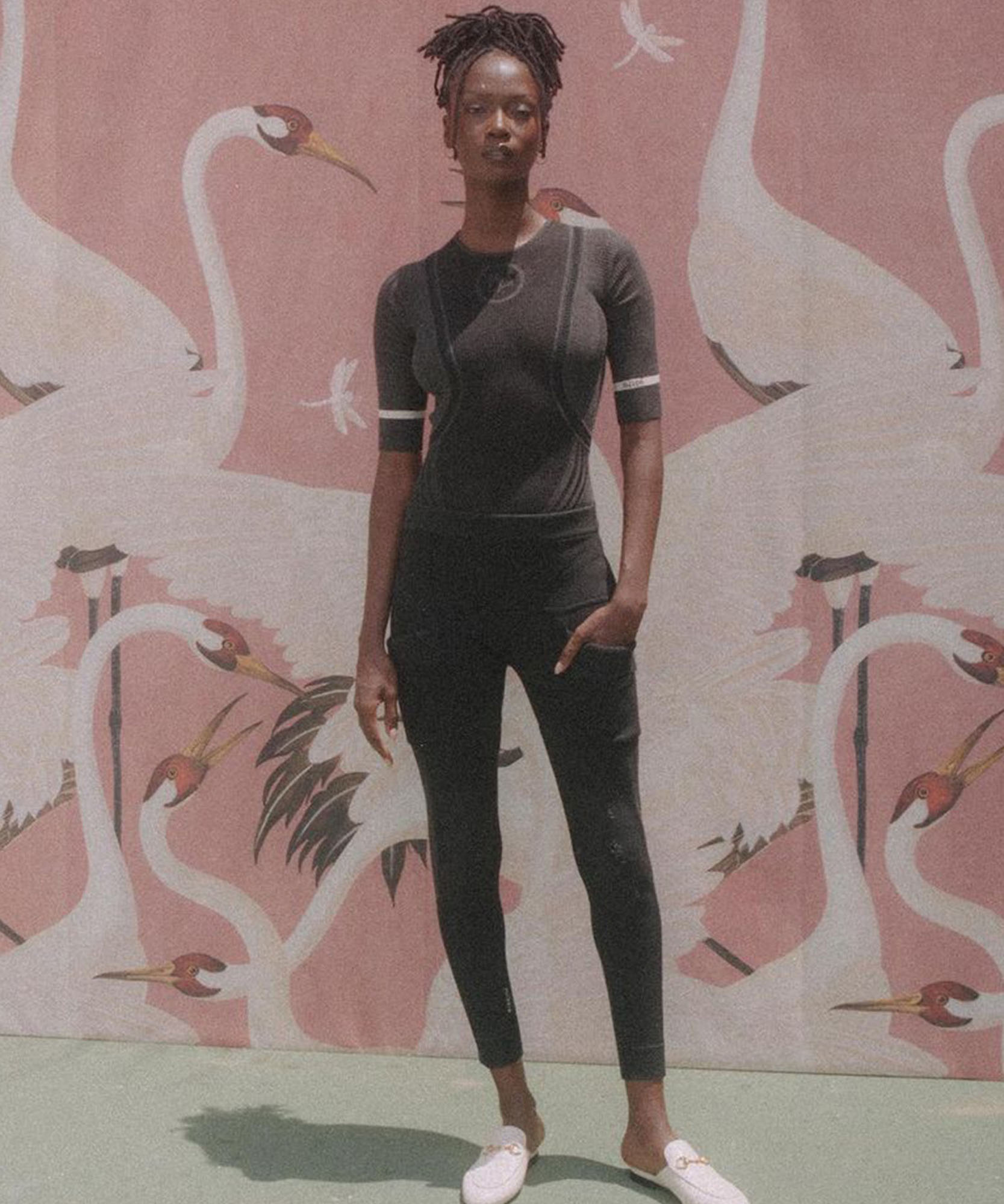 a photo of a women wearing all black with a pink background