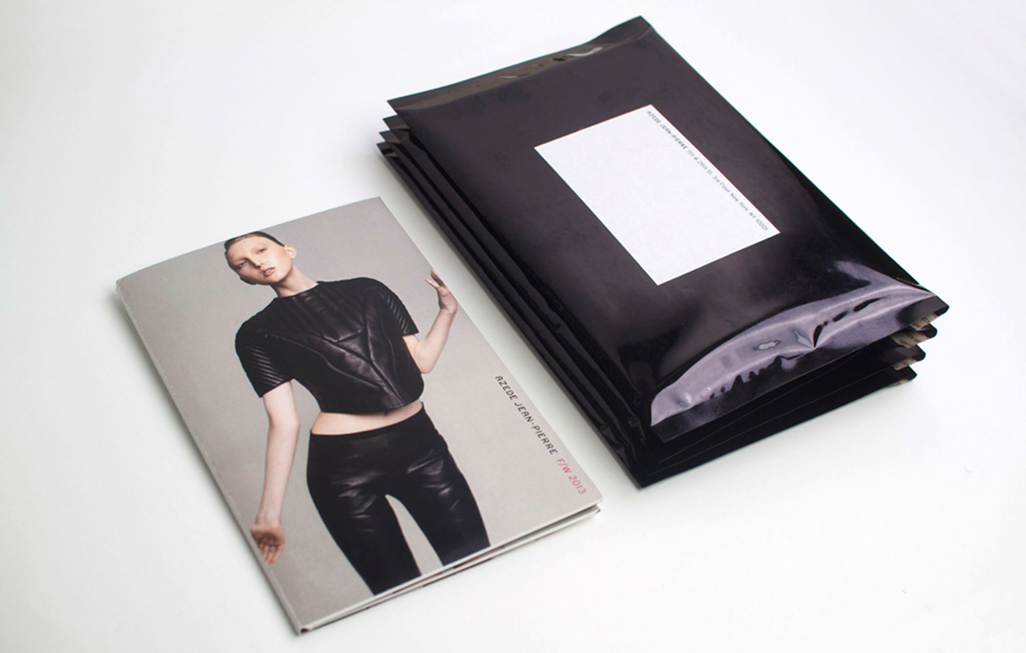a photo of a magazine with a women wearing all black beside a stack of black mailers
