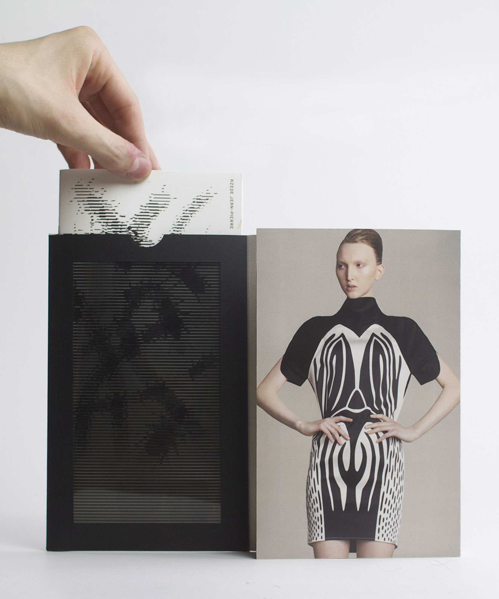 a photo of card with a hand pulling out a paper with illustrations of bees beside a women madel wearing lack and white