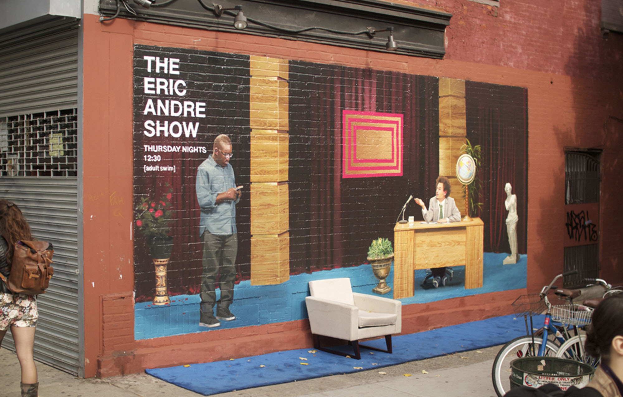 wall art on the side of the building of the eric andre show with the text of the eric andre show with a photo of eric andre sitting down with a real white chair in front