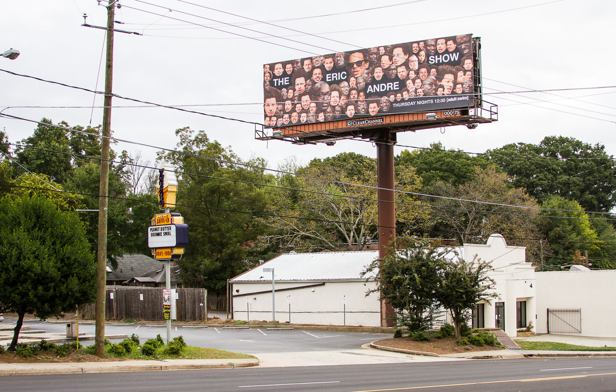 a billboard with a text that say the eric andre show with face cut outs surrounding the text in front of a building