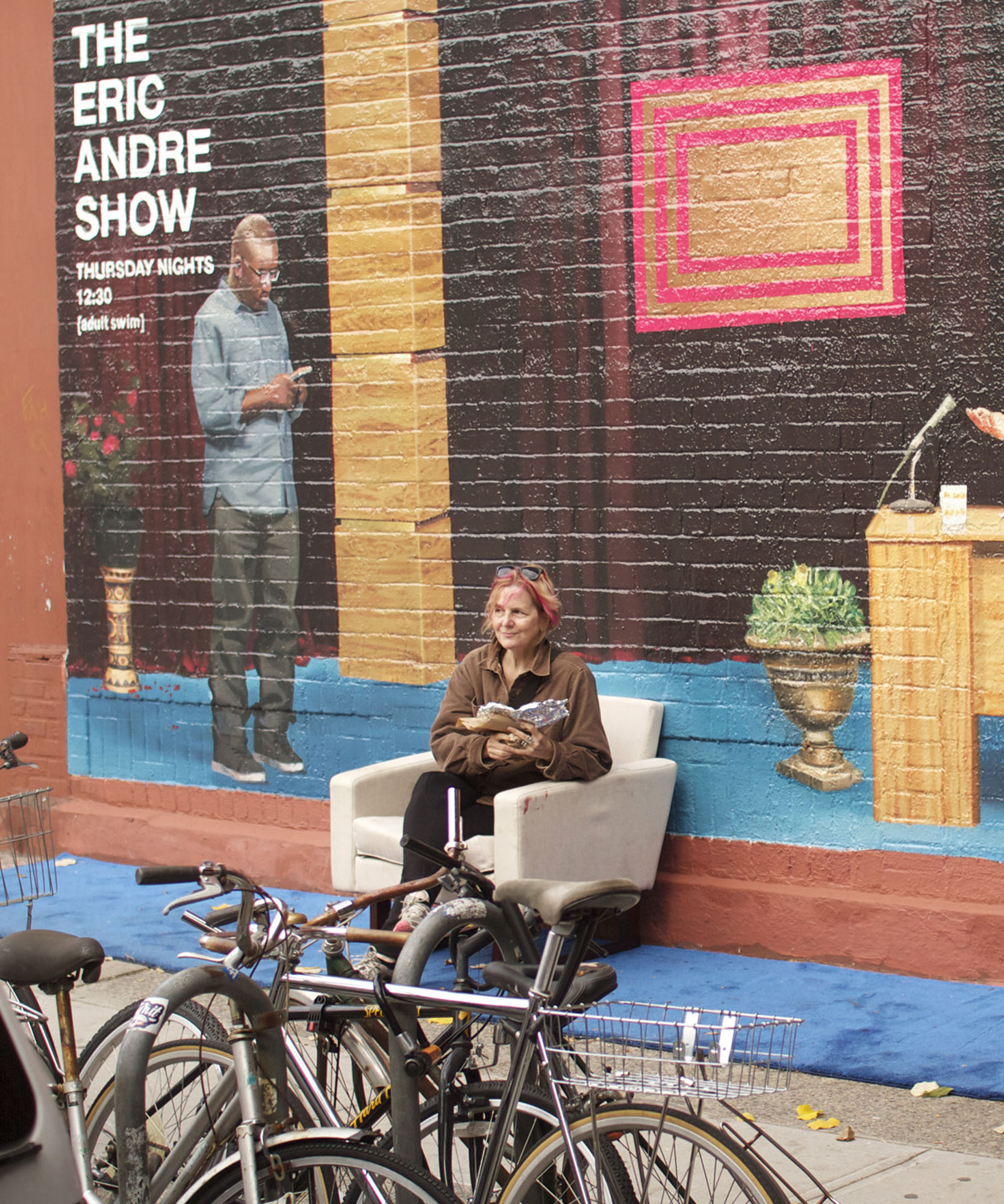 a women sitting in a white chair in front of wall art