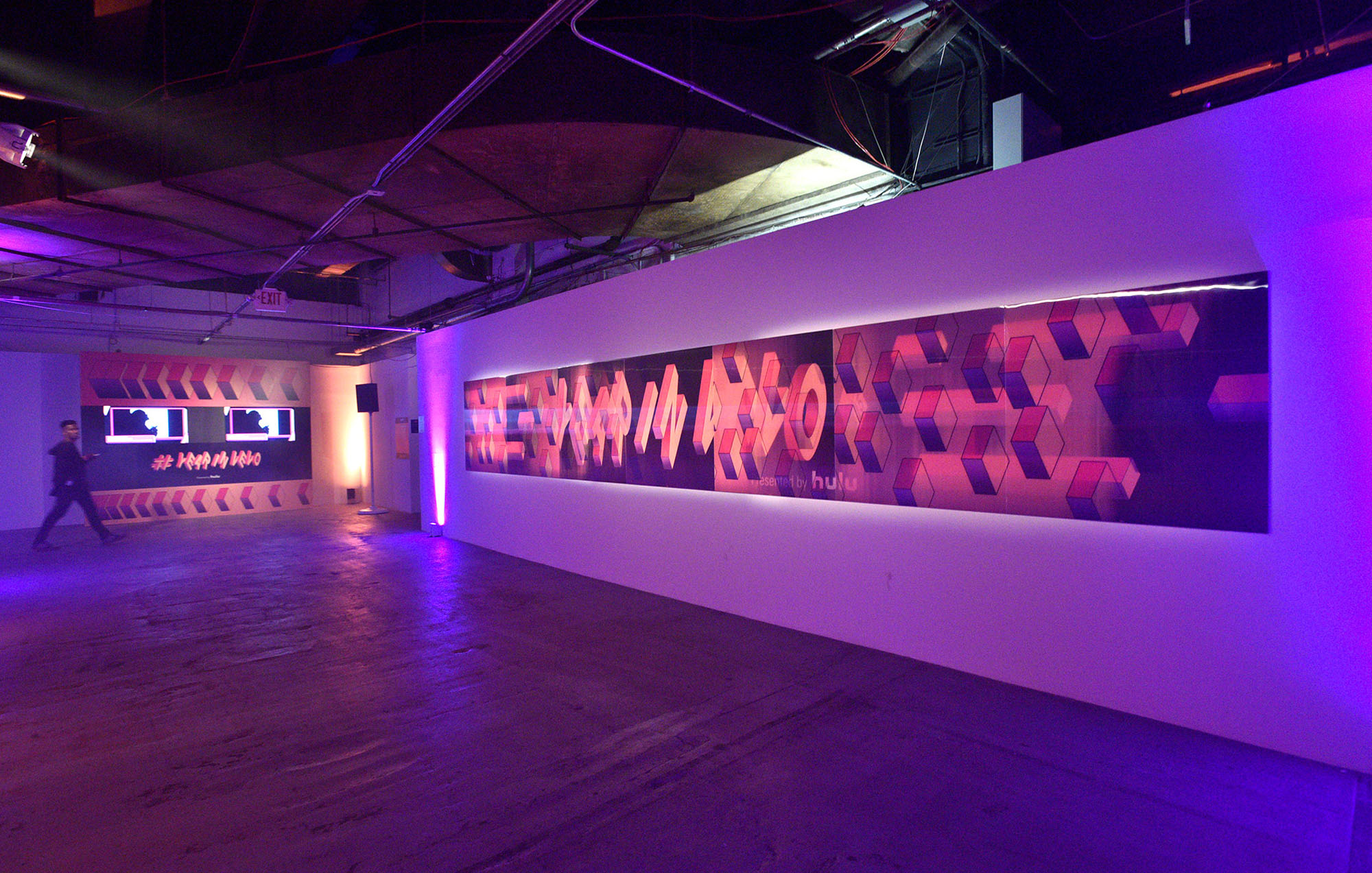 a long hallway with concrete floors and the vevo in a year logo on the wall with purple light in the background