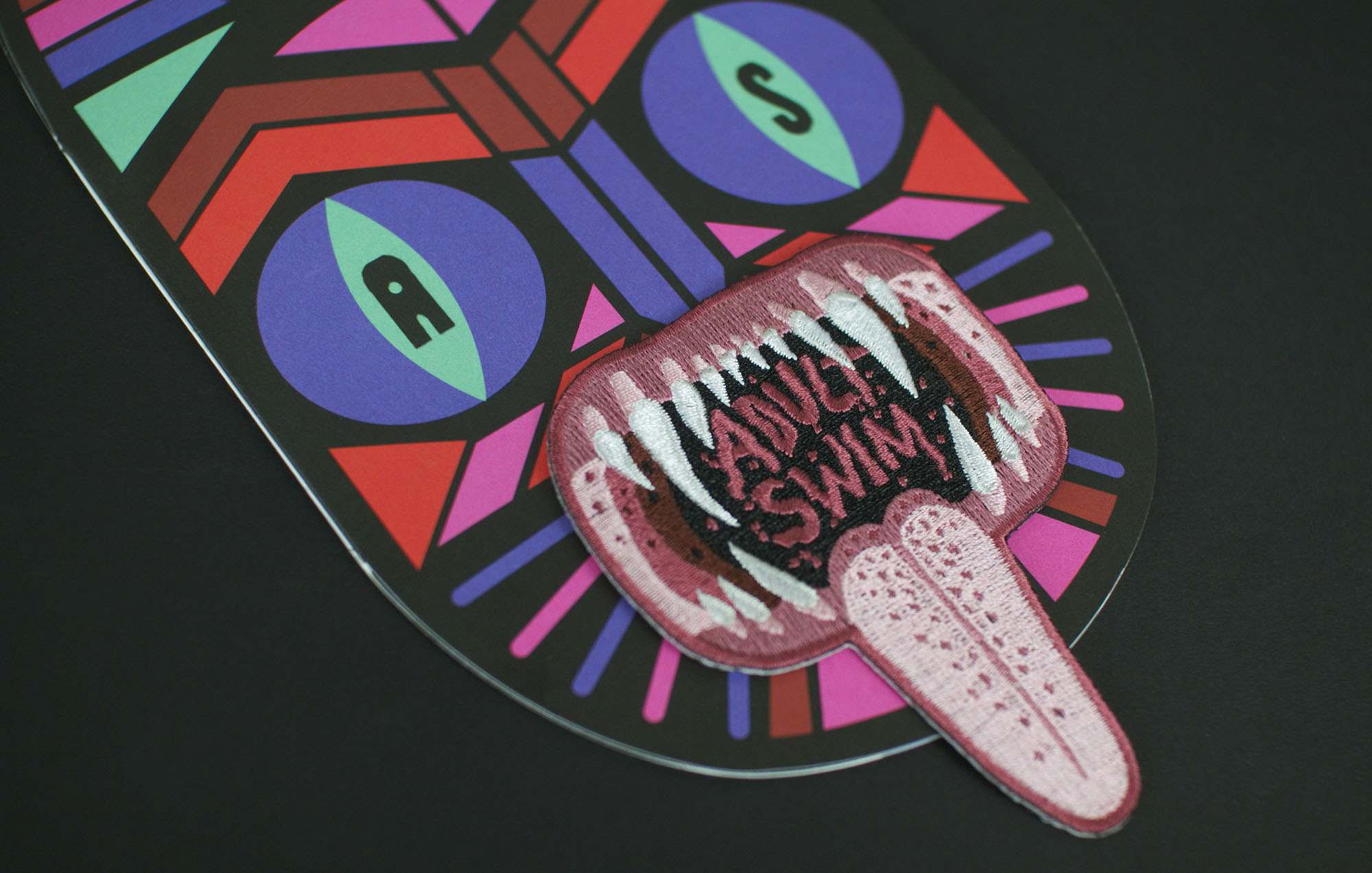 a up close view of a multi colored cat with an open mouth that says adult swim inside with a long tongue hanging out