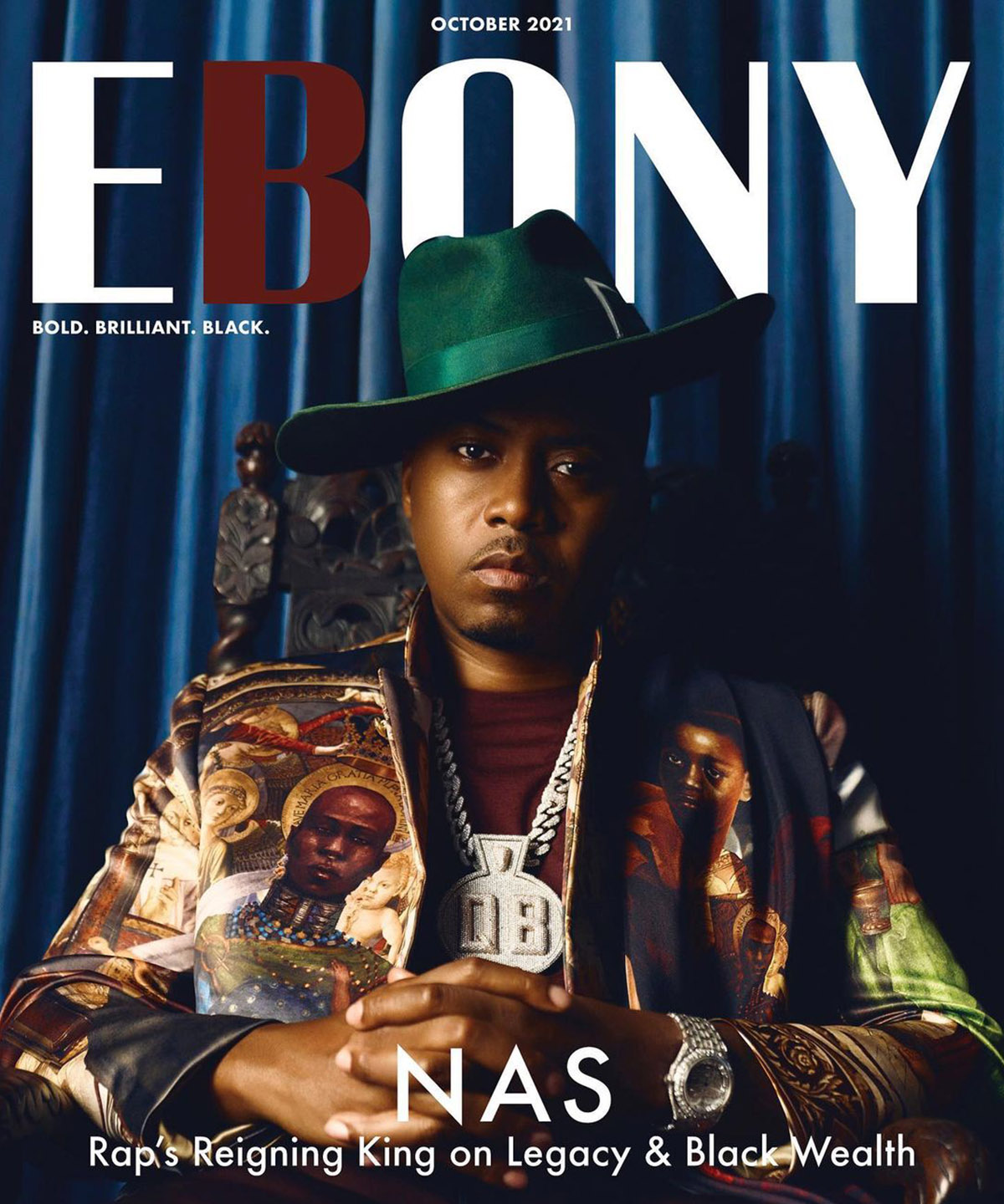 Nas wearing green hat and large silver chain with a blue curtain background