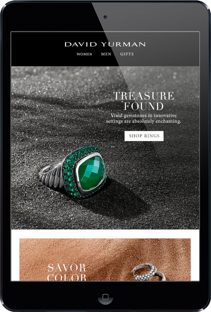 A single silver ring with a green stone in the center sitting on top of black sand displayed on ipad with the David yurman logo on top