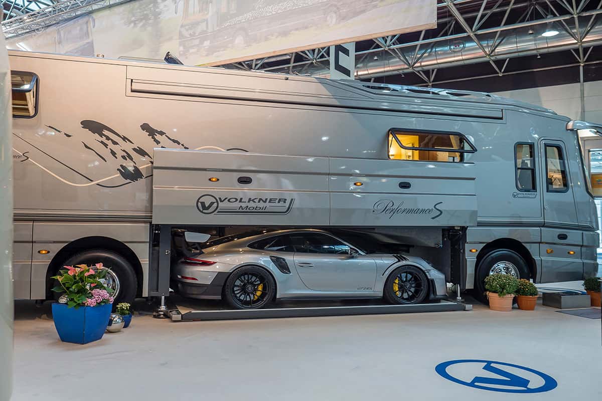 Luxus-Wohnmobil an einem Messestand mit Porsche in der Heckgarage