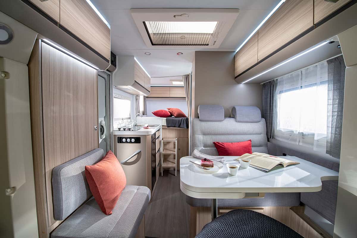 Blick in die wohliche Dinette des Adria Wohnmobils mit der Küche im Hintergrund