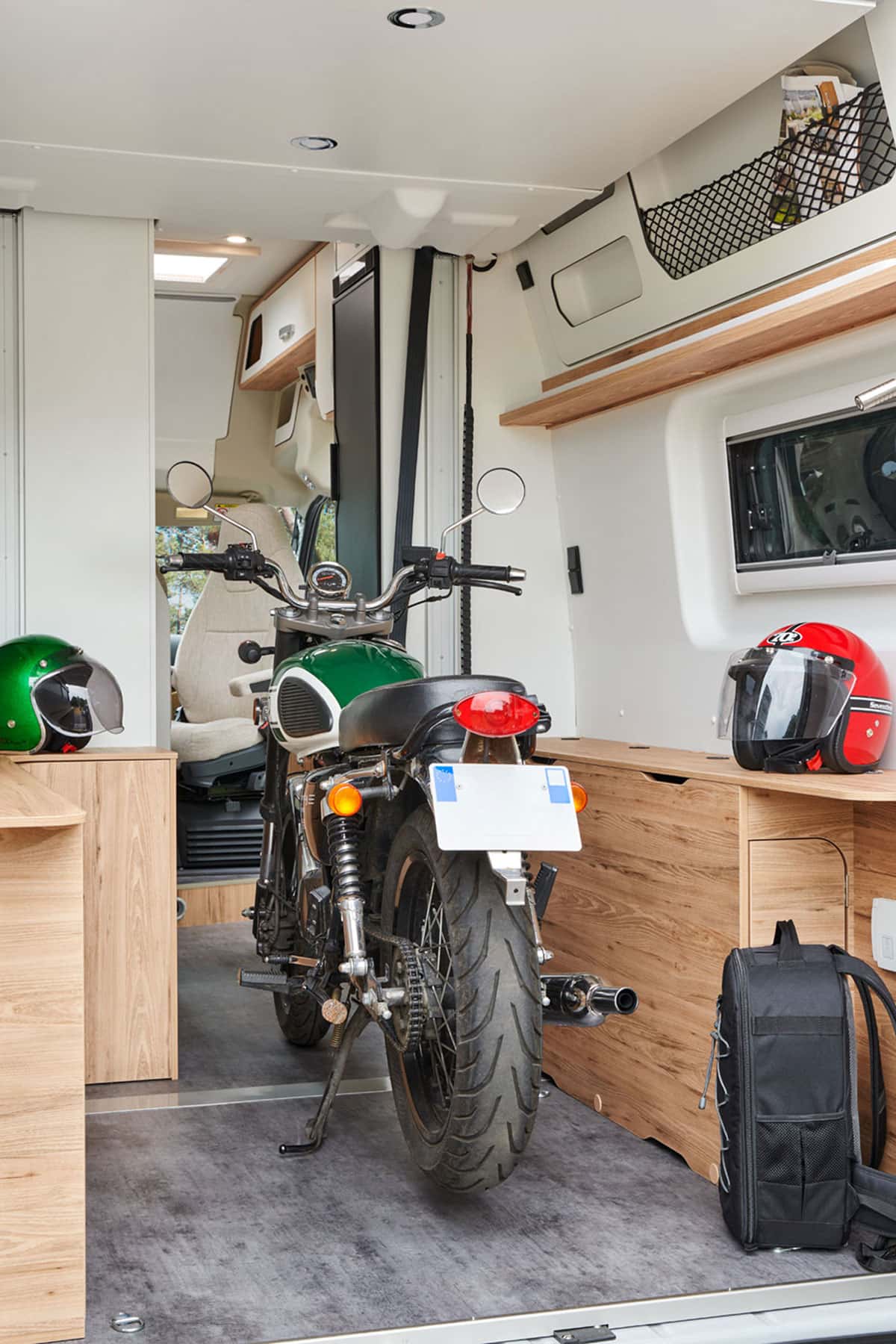 Motorrad und zwei Helme in Wohnmobil-Heck in hellen Farbtönen