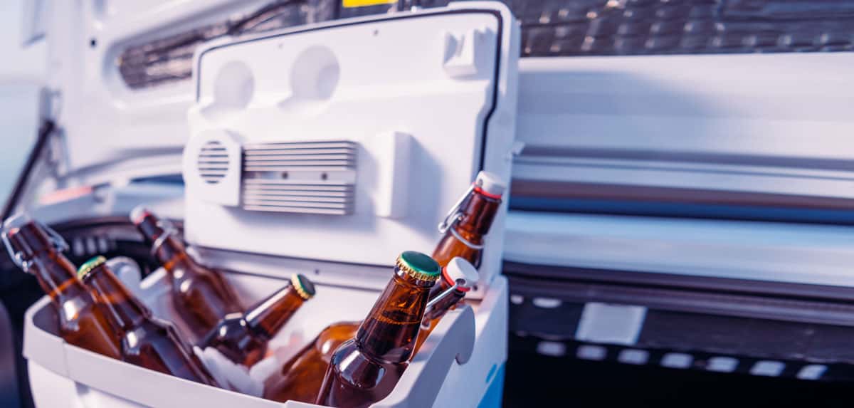 Mehrere Flaschen Bier liegen in Eis in einer offenen Kühlbox