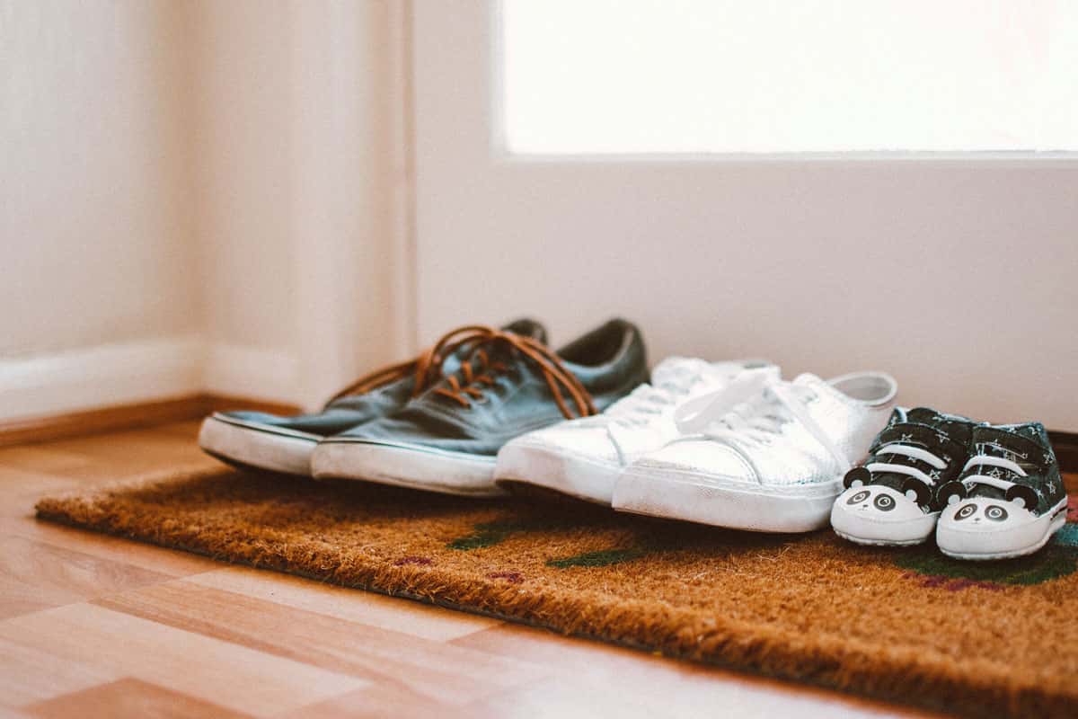 Zwei Paar grosse Schuhe und ein Paar Kinderschuhe stehen auf einer Fussmatte
