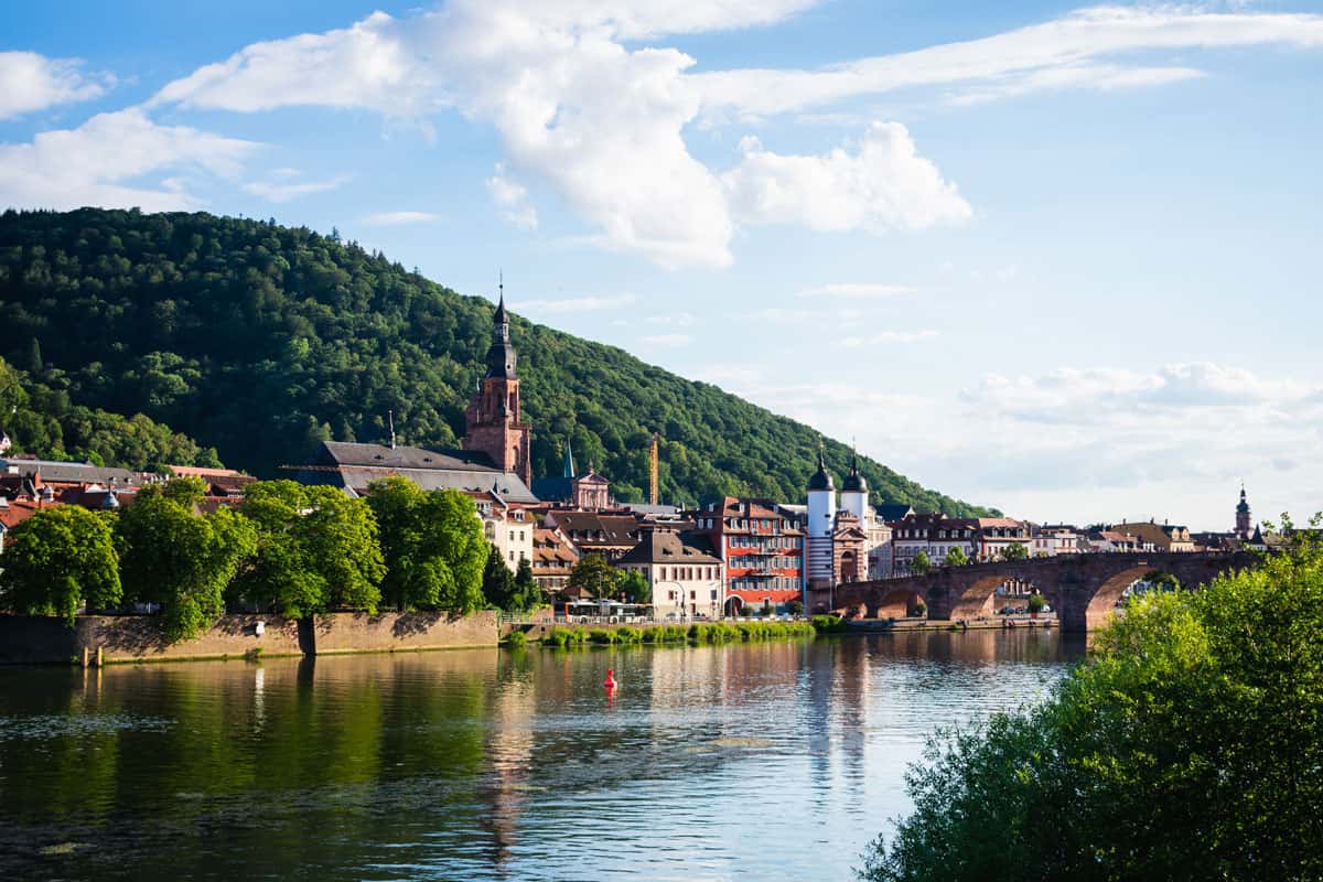 Zu sehen ist ein idyllisches deutsches Städtchen am Bergfuß an einem Fluss.